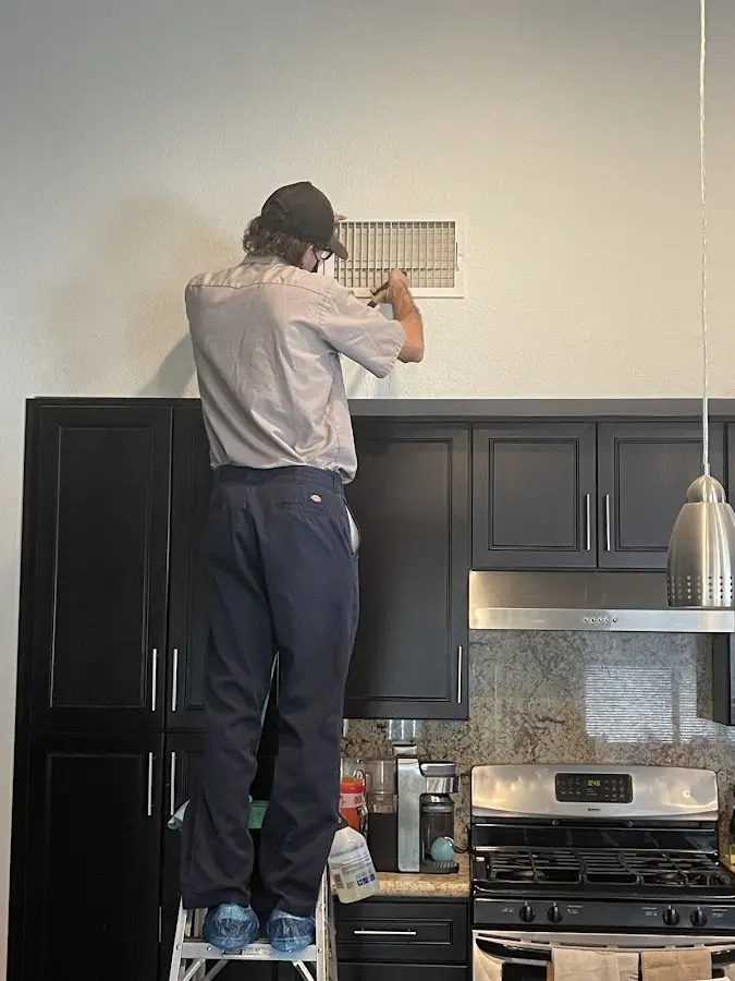 Technician inspecting an air vent during HVAC service in Hopkinton